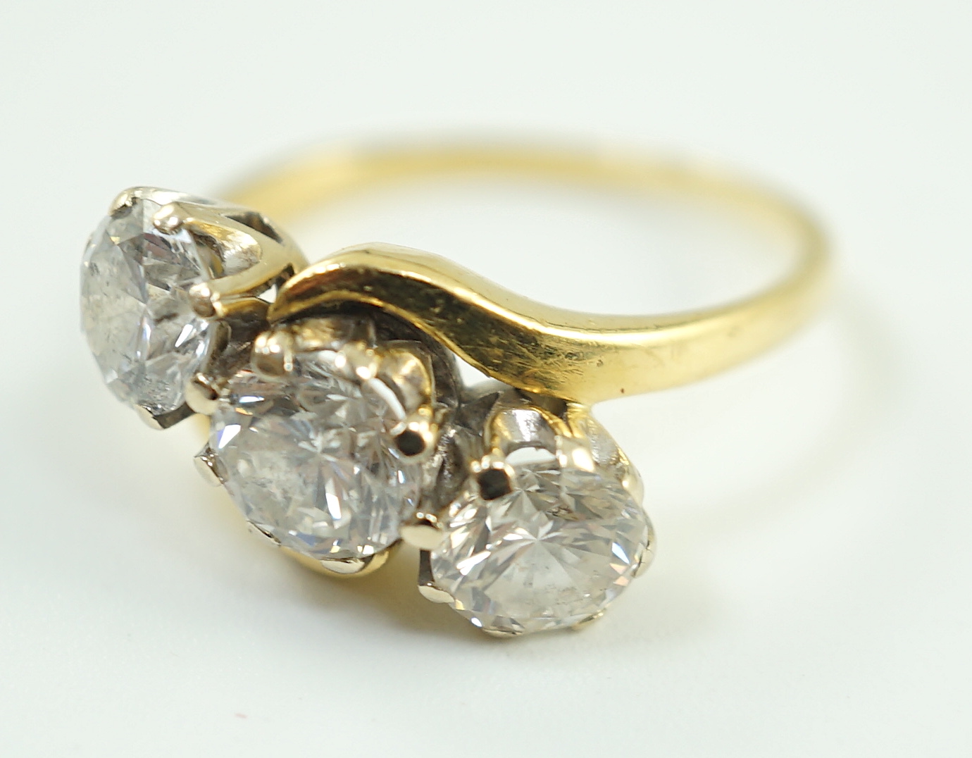 A modern 18ct gold and three stone diamond set crossover ring
